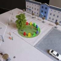 Modell der Bahnhofsinsel von oben mit Häuserfassaden, grüner Insel, Baum und farbigen Buchstaben