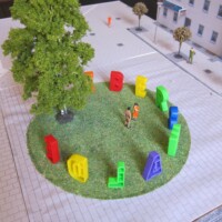 Grüne Insel mit großem Baum, bunte 3D-Buchstaben im Kreis, Figuren und weiße Platzfläche mit Häusern