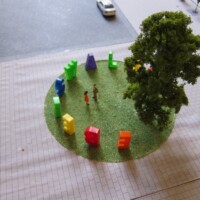 Luftaufnahme des Insel-Modells mit rundem grünem Platz, Gebäuden und Miniaturfiguren