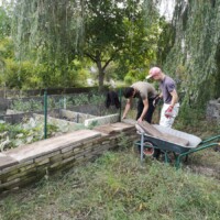 Zwei Menschen bauen an einer Beeteinfassung aus Steinplatten