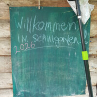 Eine Wandtafel am Schuppen mit der Aufschrift "Willkommen im Schulgarten"