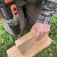 Eine person boht Löcher in ein Stück Holz