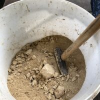 Eine große Schüssel mit trockenem Lehm, der zerstampft wird