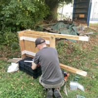 Eine person verschraubt einen Holzkasten mit Beinen