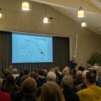 Ein Diskussionteilnehmer erklärt eine grafische Darstellung auf der Leinwand